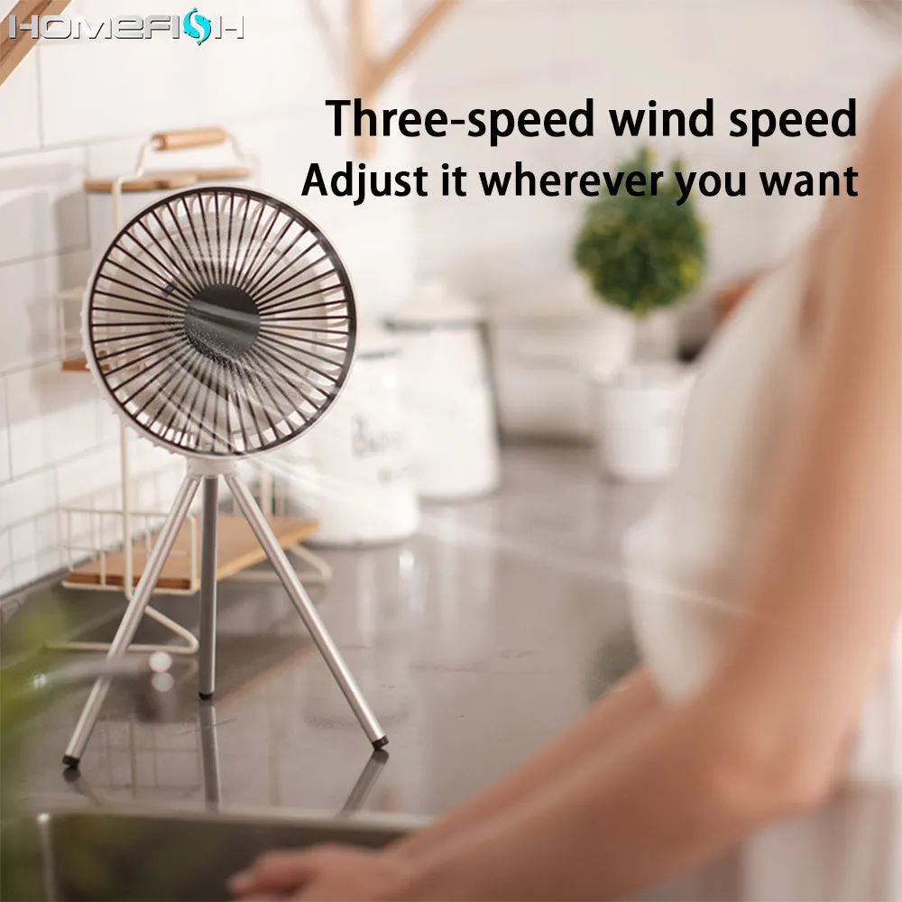 Tripod camping fan in dark grey on a wooden table showing blades and USB port