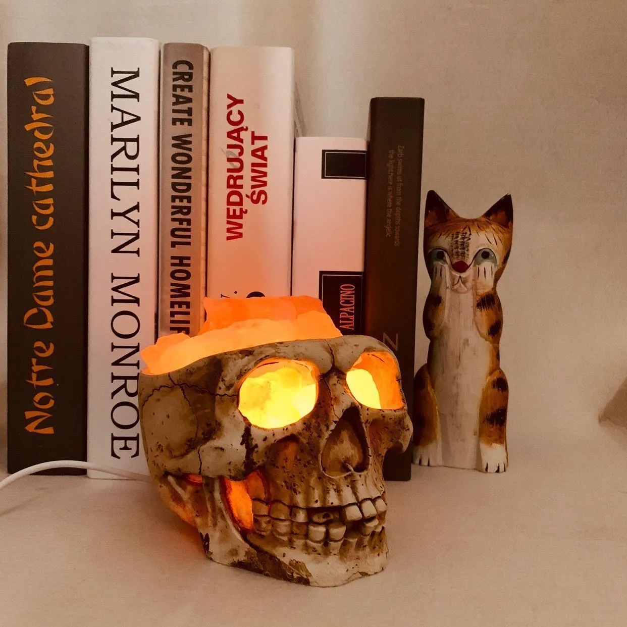 Skull-shaped Himalayan crystal salt lamp with USB dimmable LED showing warm amber light on a resin base