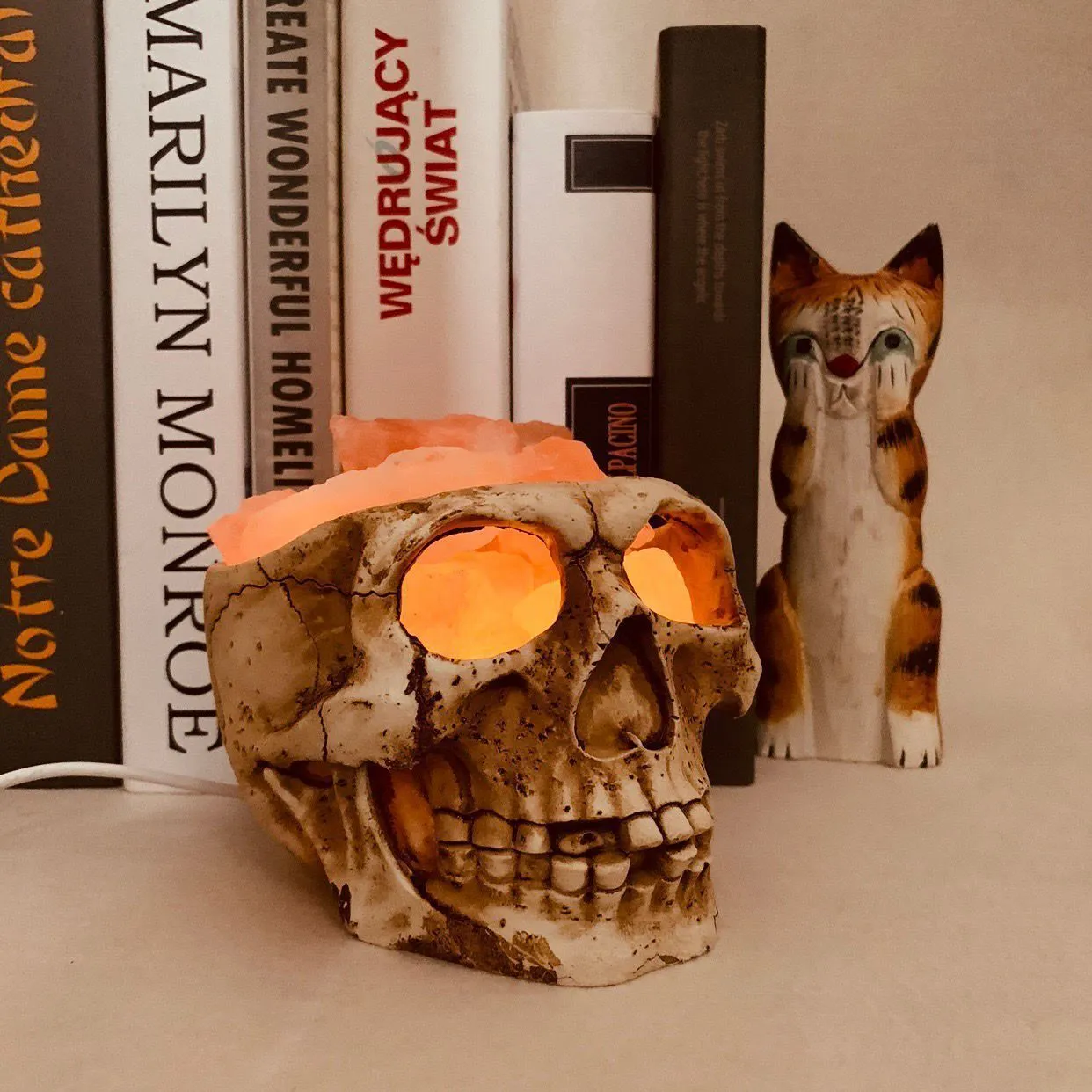 Skull-shaped Himalayan crystal salt lamp with USB dimmable LED showing warm amber light on a resin base