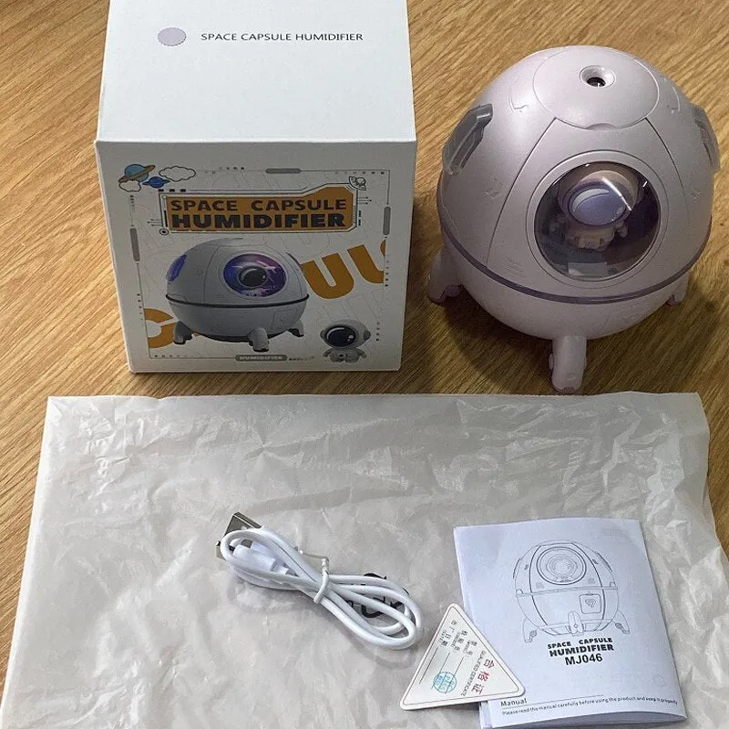 Purple astronaut space capsule USB humidifier with colourful LED lights on desktop