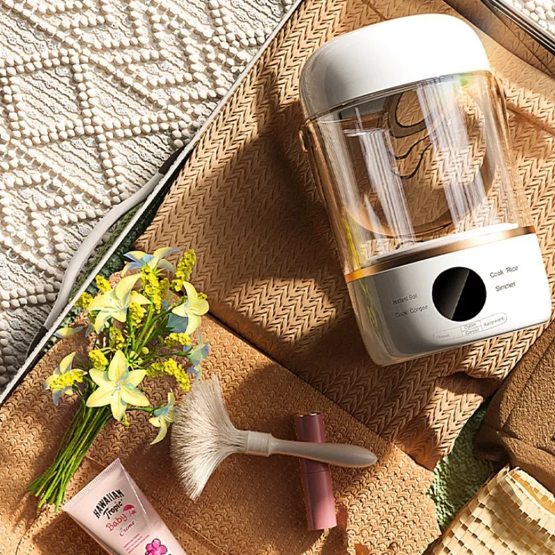 Personal portable electric stew cooker with transparent glass pot and fibreglass body on a desk.