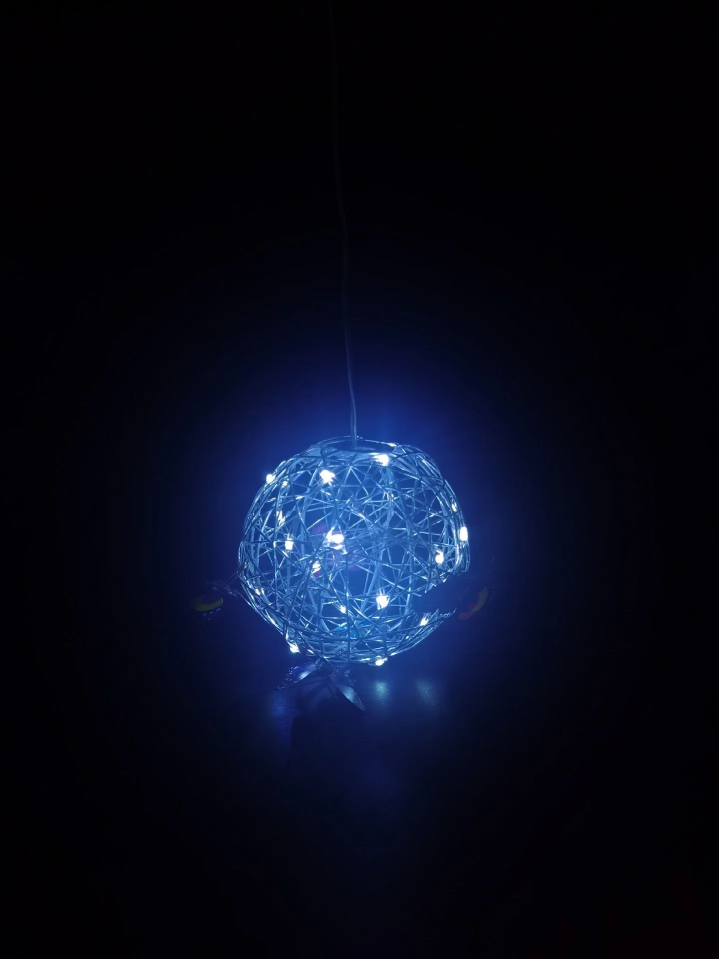 White outdoor solar ball light with random colour butterfly decorations on a garden lawn