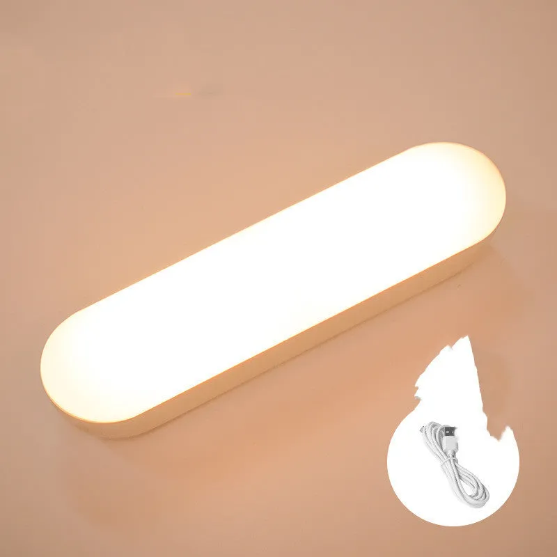 Fully automatic unplugged bedside night light for dormitory with magnetic base, USB rechargeable, showing yellow light mode on a dark bedside table