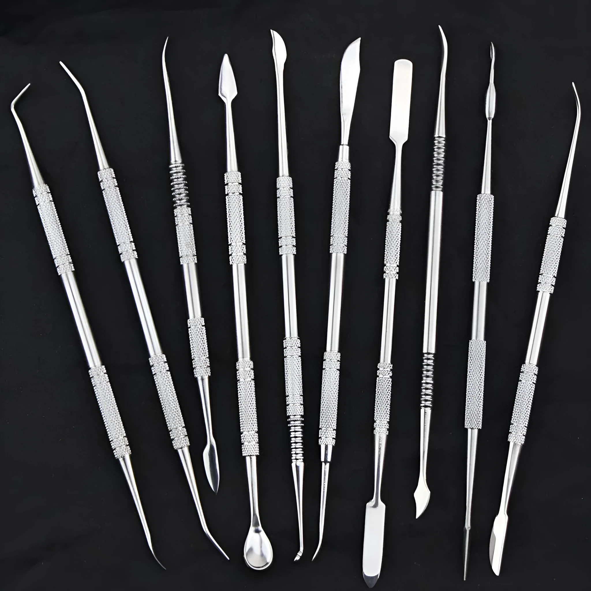 Ten stainless steel clay knives with photo colour handles arranged on a surface for pottery sculpting work.