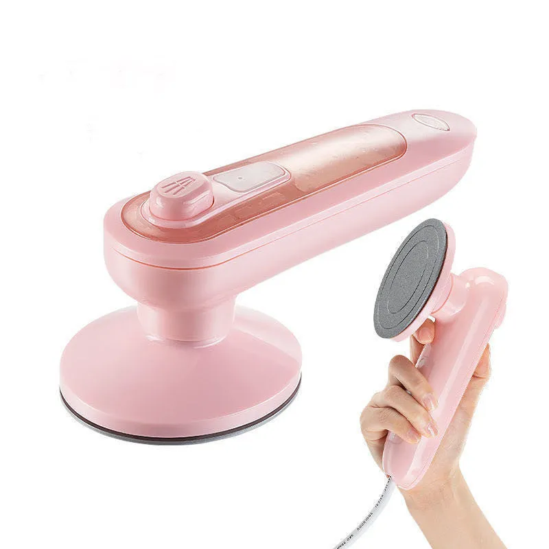 Pink portable electric iron with EU and US plug adapters on a white background