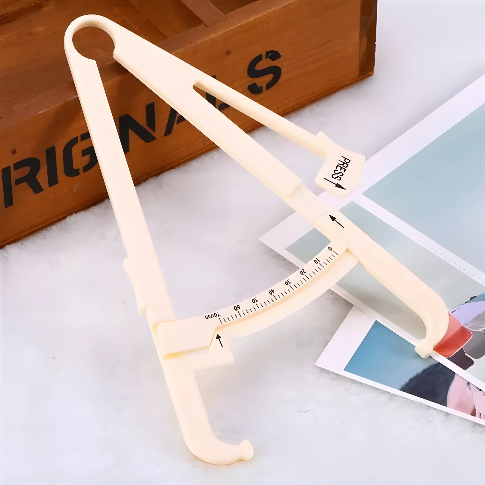 Compact acrylic fat caliper for body fat measurement, showing size and scale.