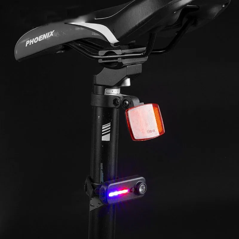 Black bicycle warning taillight with clip and strap on a backpack strap, showing red and blue flash mode