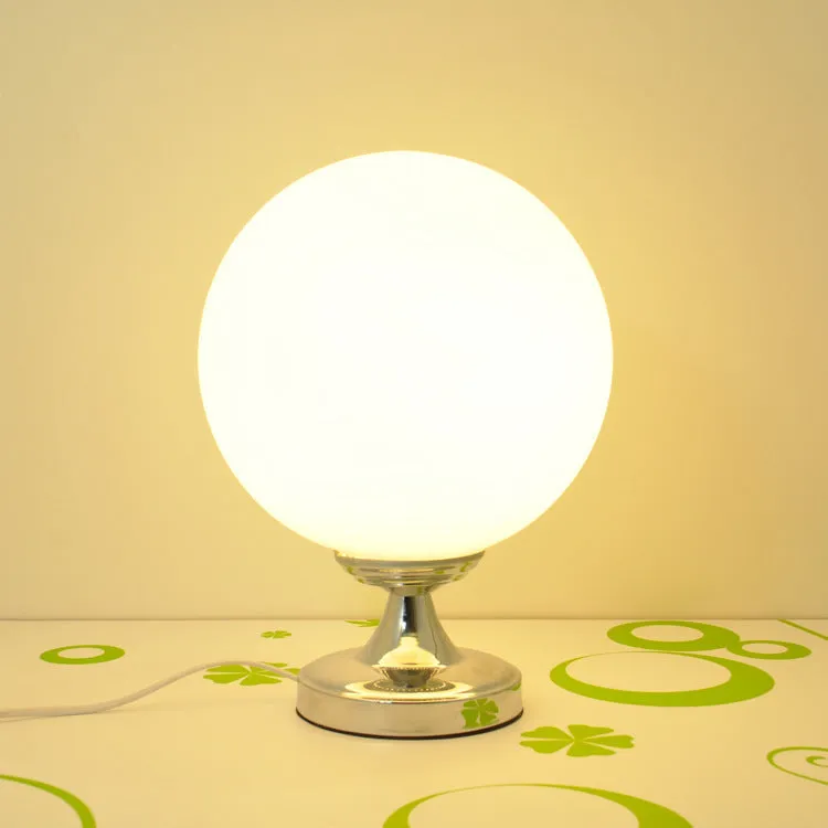 Creative football-shaped glass table lamp with dimmer switch on a desk in a modern living room