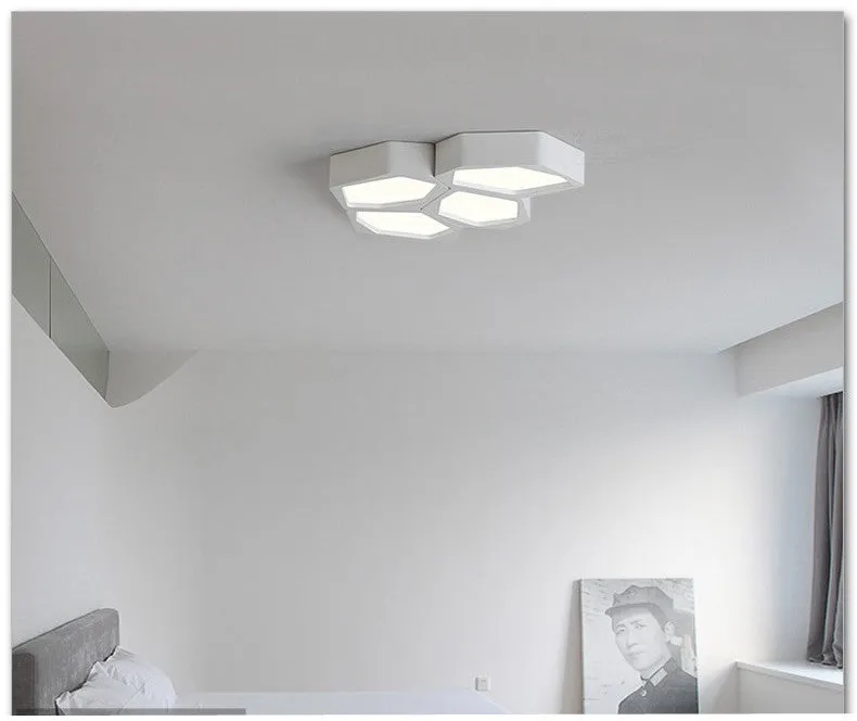 Geometric shaped iron LED light with black frame and remote control on a table.