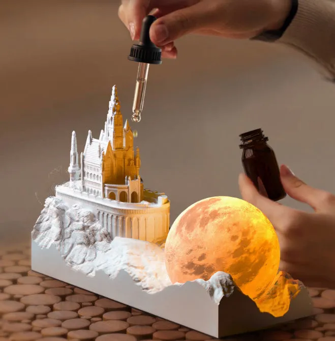 Mountain-shaped night light with LED touch control, essential oil bottle, and gift card on a wooden desk