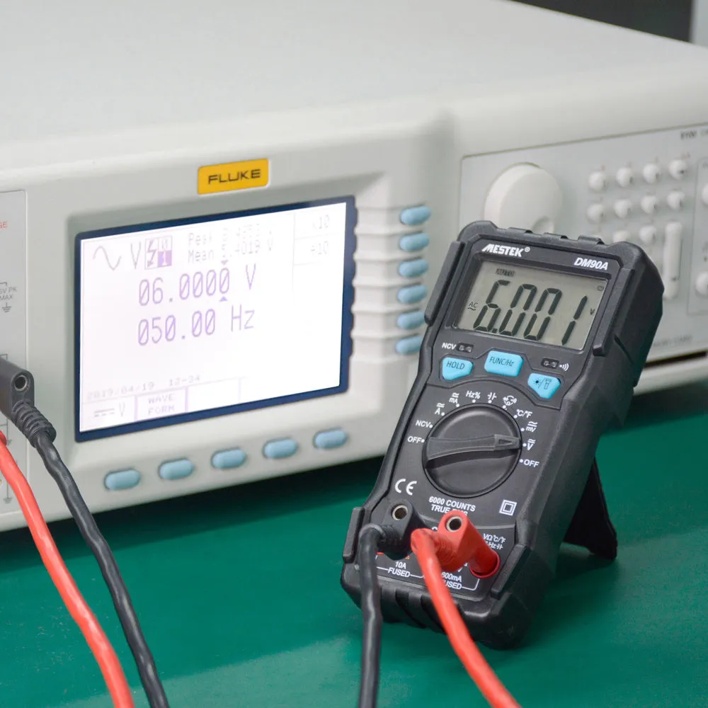 DM90A digital multimeter with test leads on a workbench, showing its display and temperature probe