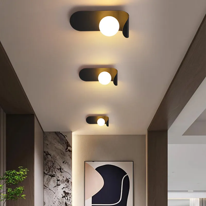 Modern minimalist wall lamp in black finish with LED warm light on a bedroom wall beside bed