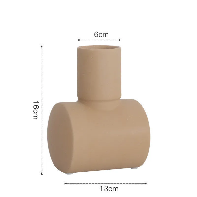 A simple hammer-textured ceramic vase in a Morandi colour on a wooden surface.
