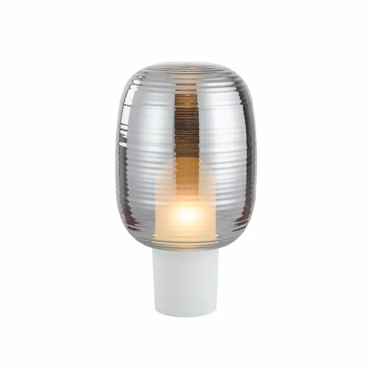 Simple modern glass table lamp on a table, shown in cognac and smoky grey colour options.