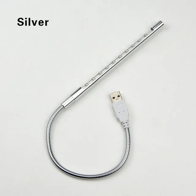 Black spiral USB desk lamp with aluminium shade on a desk next to a laptop
