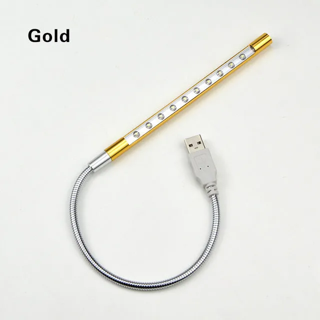 Black spiral USB desk lamp with aluminium shade on a desk next to a laptop