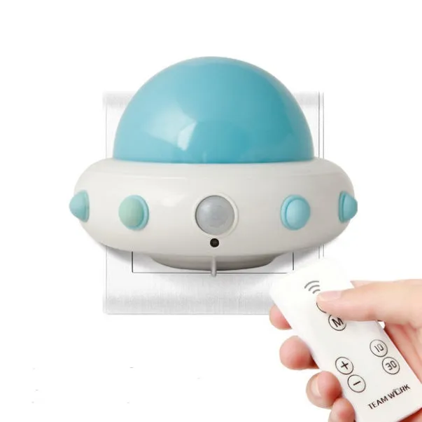 Blue UFO-shaped bedside night light with remote control on a wooden table.