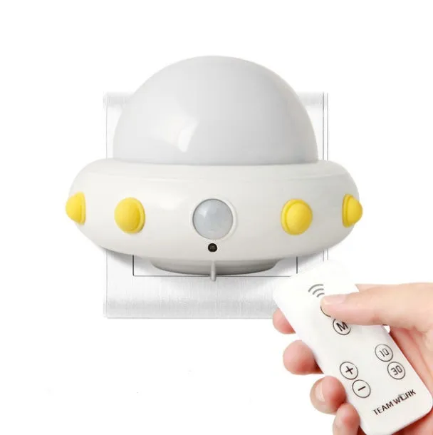 Blue UFO-shaped bedside night light with remote control on a wooden table.