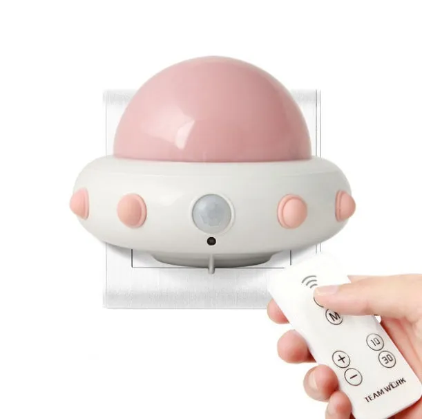 Blue UFO-shaped bedside night light with remote control on a wooden table.