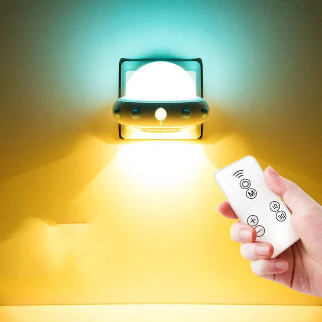 Blue UFO-shaped bedside night light with remote control on a wooden table.