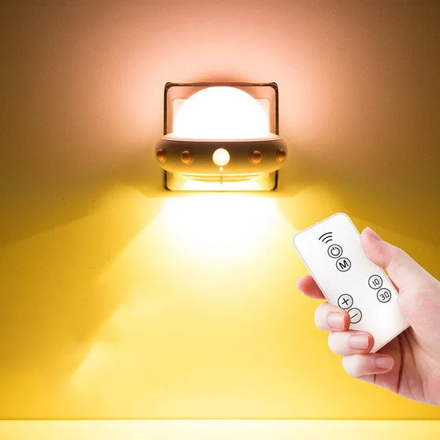 Blue UFO-shaped bedside night light with remote control on a wooden table.