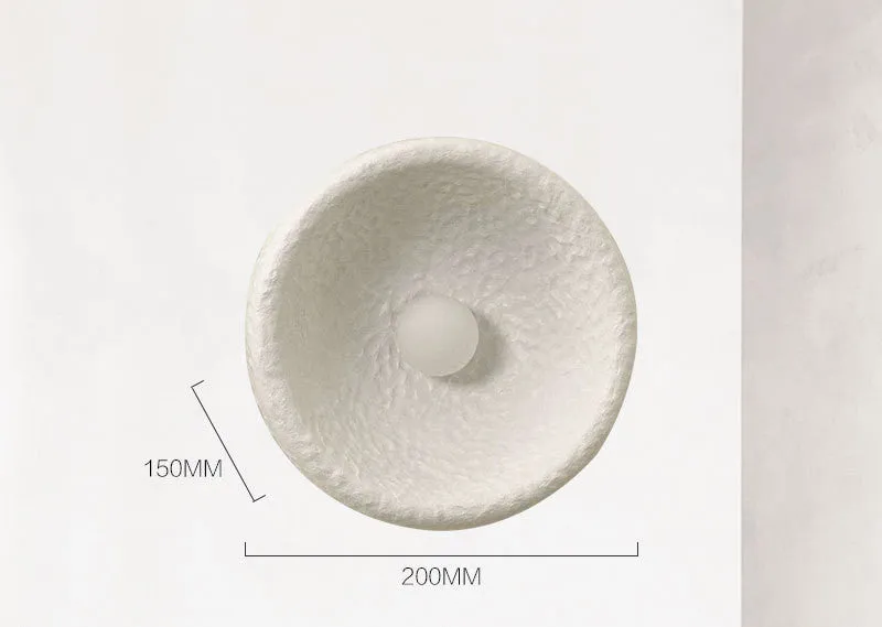 Japanese-style simple white resin wall lamp emitting warm light on a plain wall.