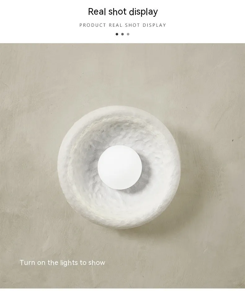 Japanese-style simple white resin wall lamp emitting warm light on a plain wall.