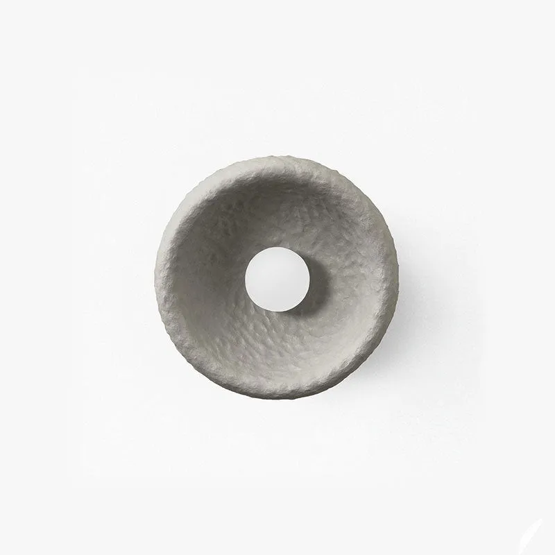 Japanese-style simple white resin wall lamp emitting warm light on a plain wall.