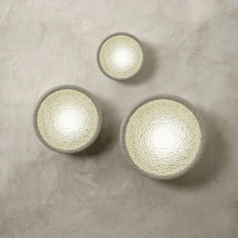 Japanese-style simple white resin wall lamp emitting warm light on a plain wall.