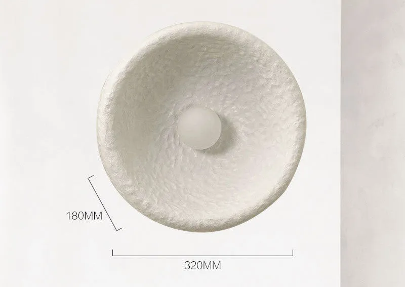 Japanese-style simple white resin wall lamp emitting warm light on a plain wall.