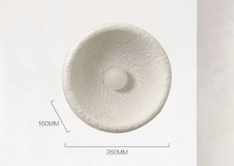 Japanese-style simple white resin wall lamp emitting warm light on a plain wall.