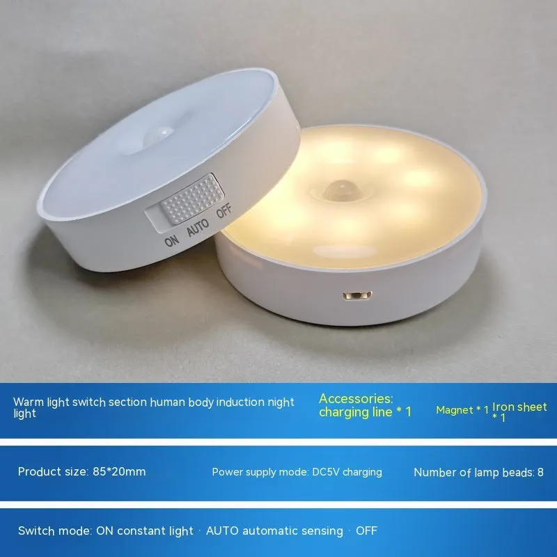 Compact white LED motion sensor night light with USB charging cable on a dark surface.
