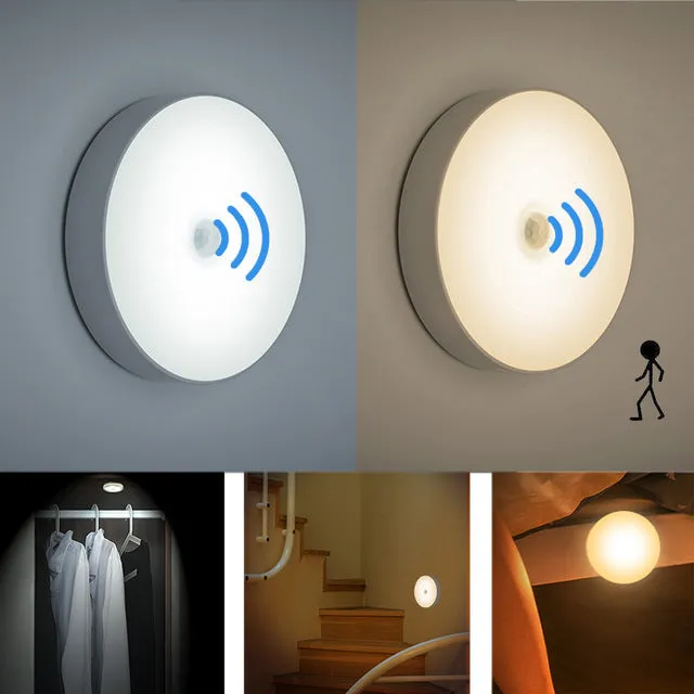 Compact white LED motion sensor night light with USB charging cable on a dark surface.