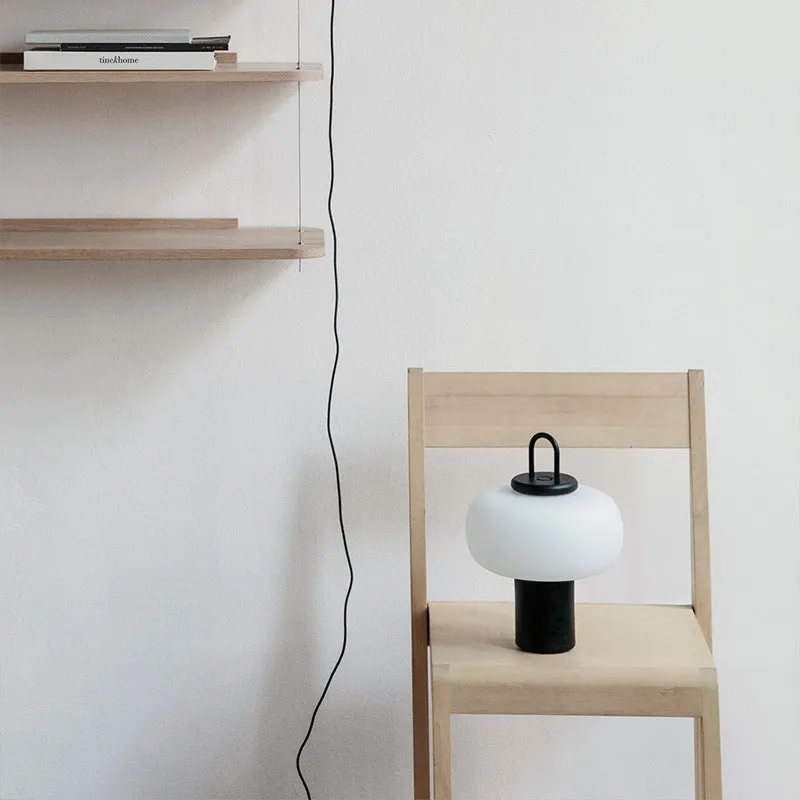Minimalist Japanese designer glass bedside table lamp with warm light for a child's room.