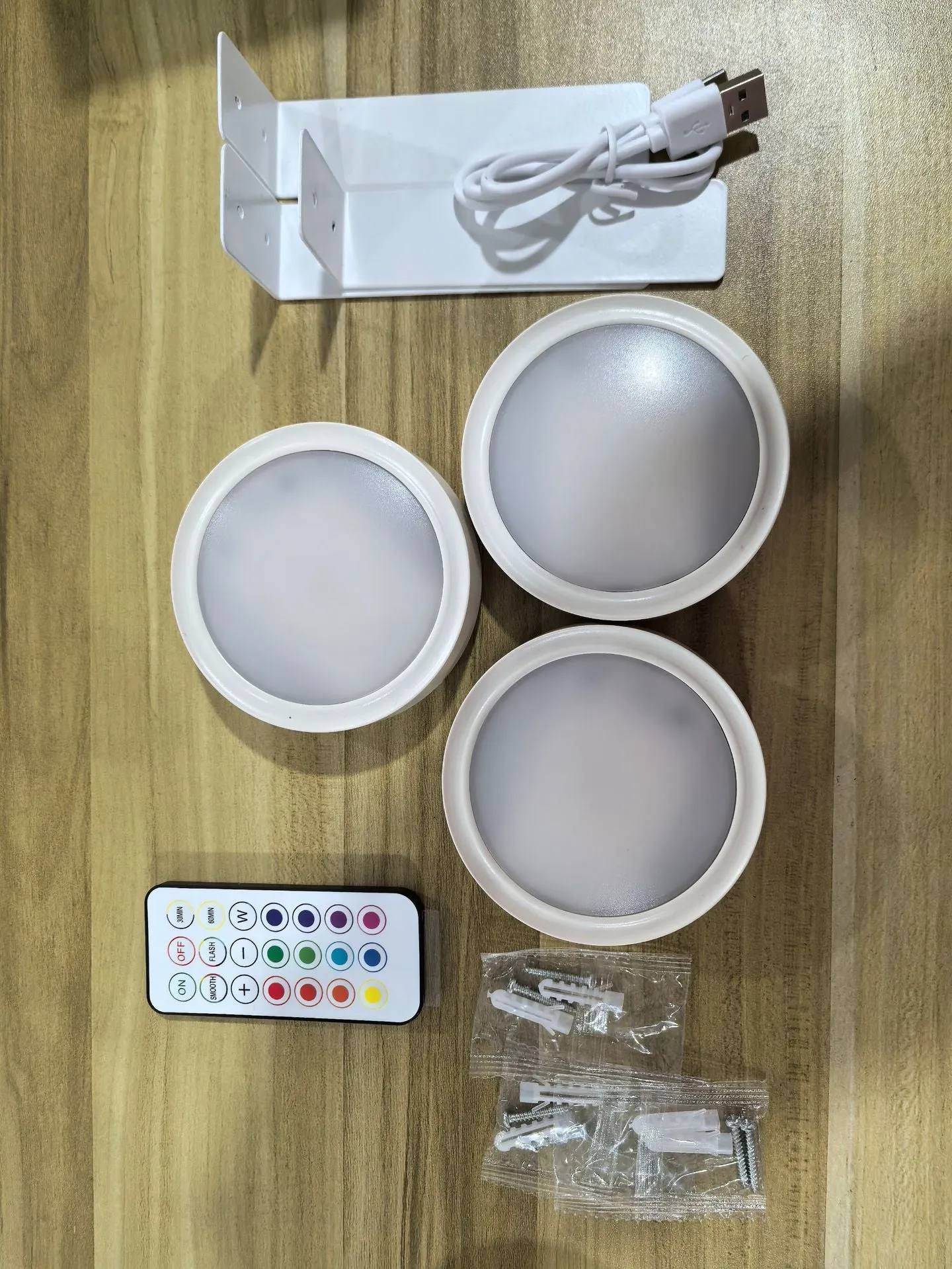 Magnetic LED light bars mounted around a painting, with a remote control on a table nearby.