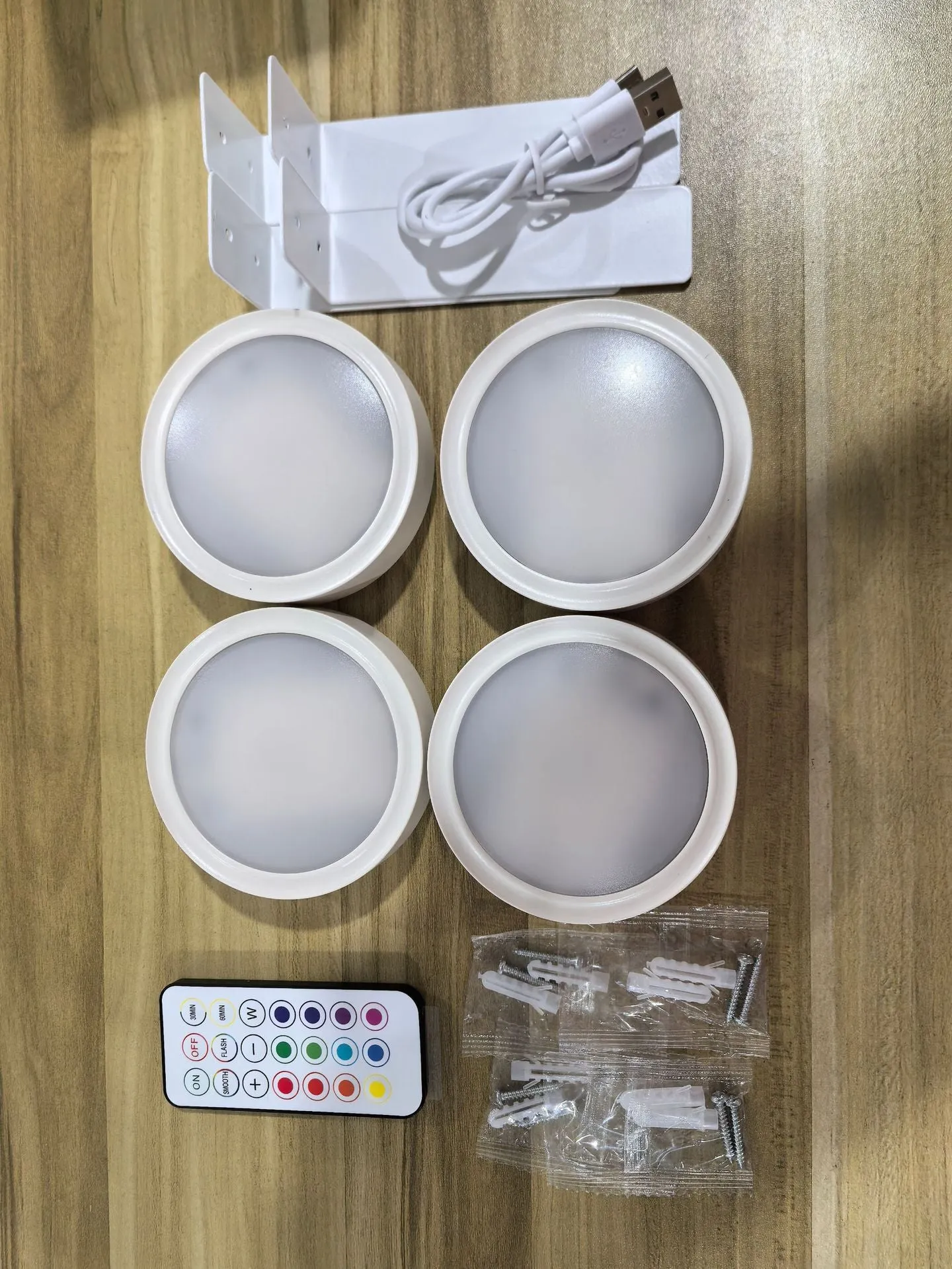 Magnetic LED light bars mounted around a painting, with a remote control on a table nearby.