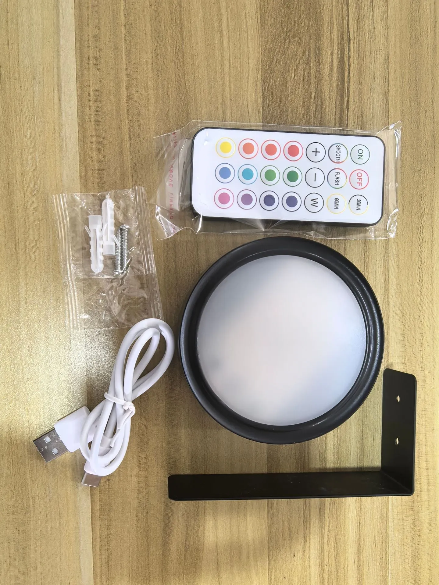 Magnetic LED light bars mounted around a painting, with a remote control on a table nearby.