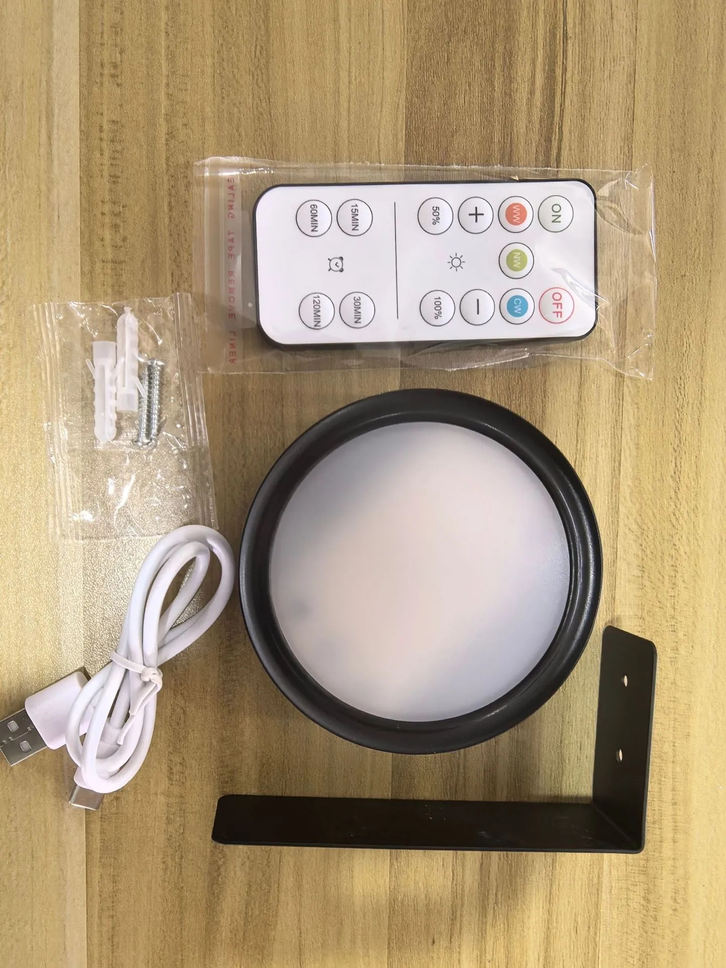Magnetic LED light bars mounted around a painting, with a remote control on a table nearby.