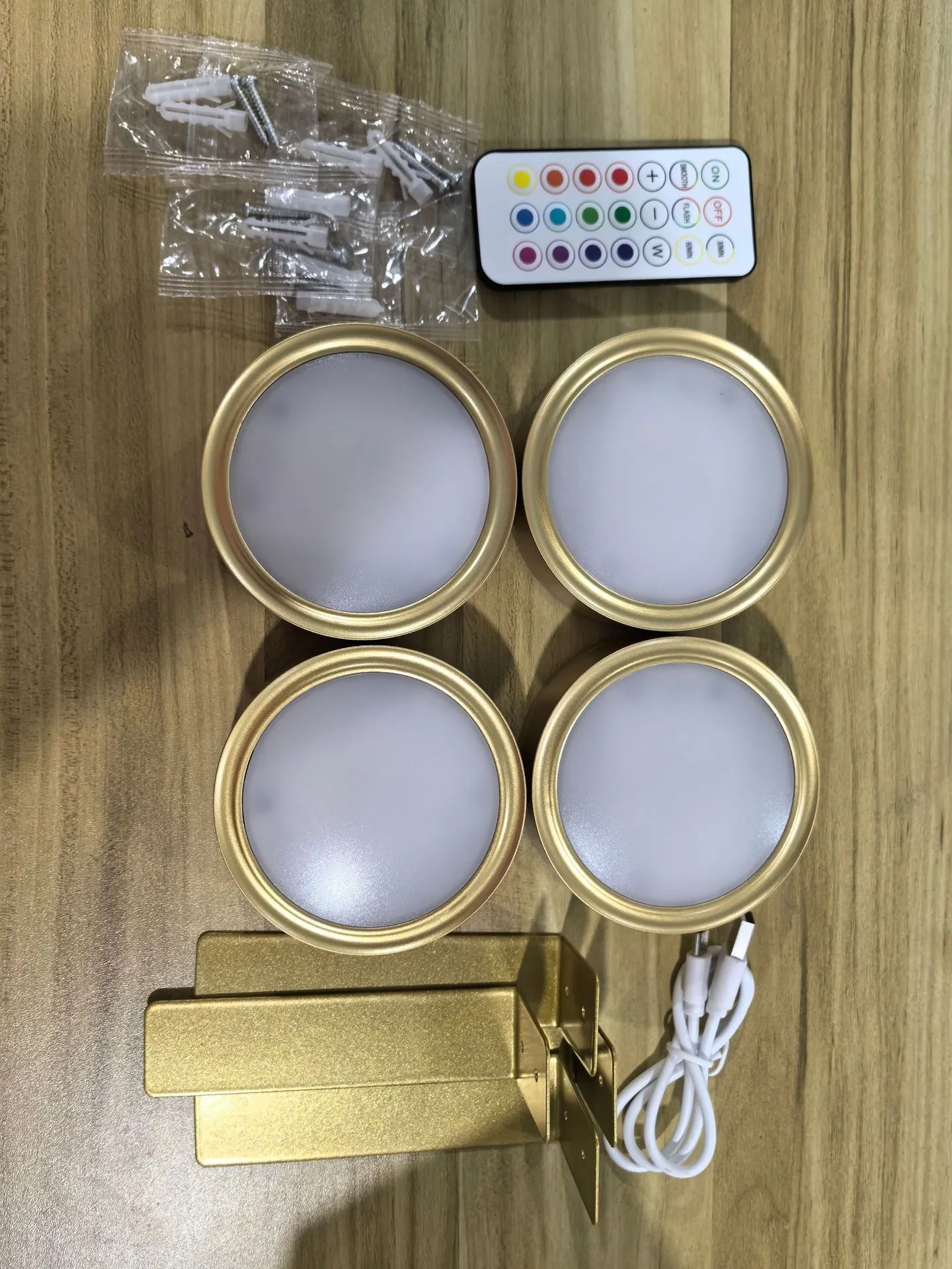 Magnetic LED light bars mounted around a painting, with a remote control on a table nearby.
