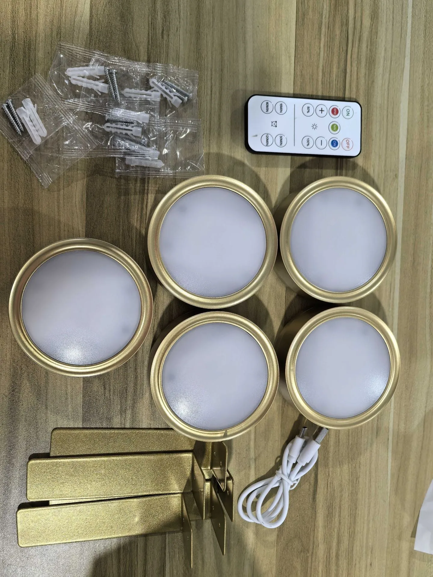 Magnetic LED light bars mounted around a painting, with a remote control on a table nearby.