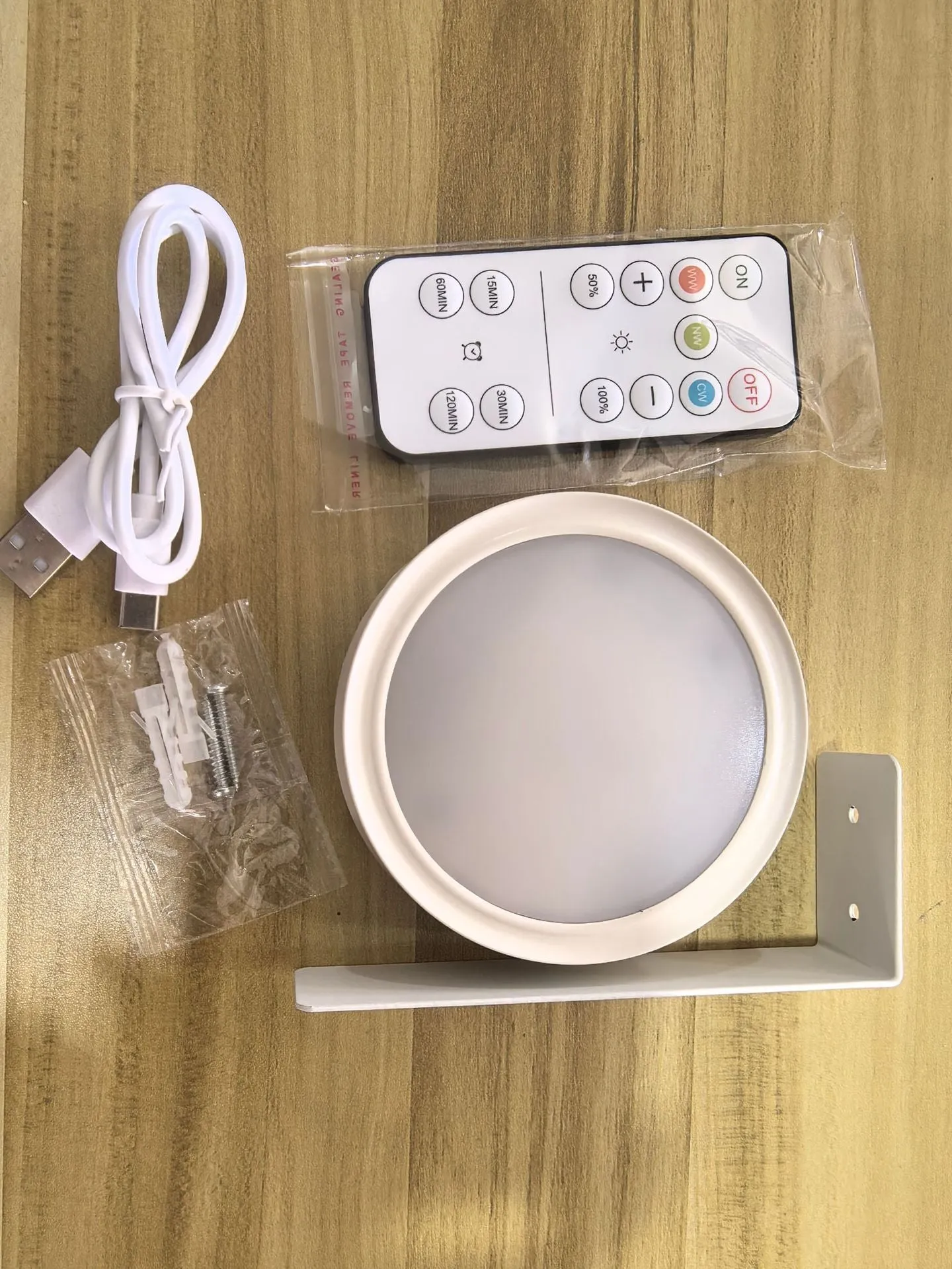 Magnetic LED light bars mounted around a painting, with a remote control on a table nearby.
