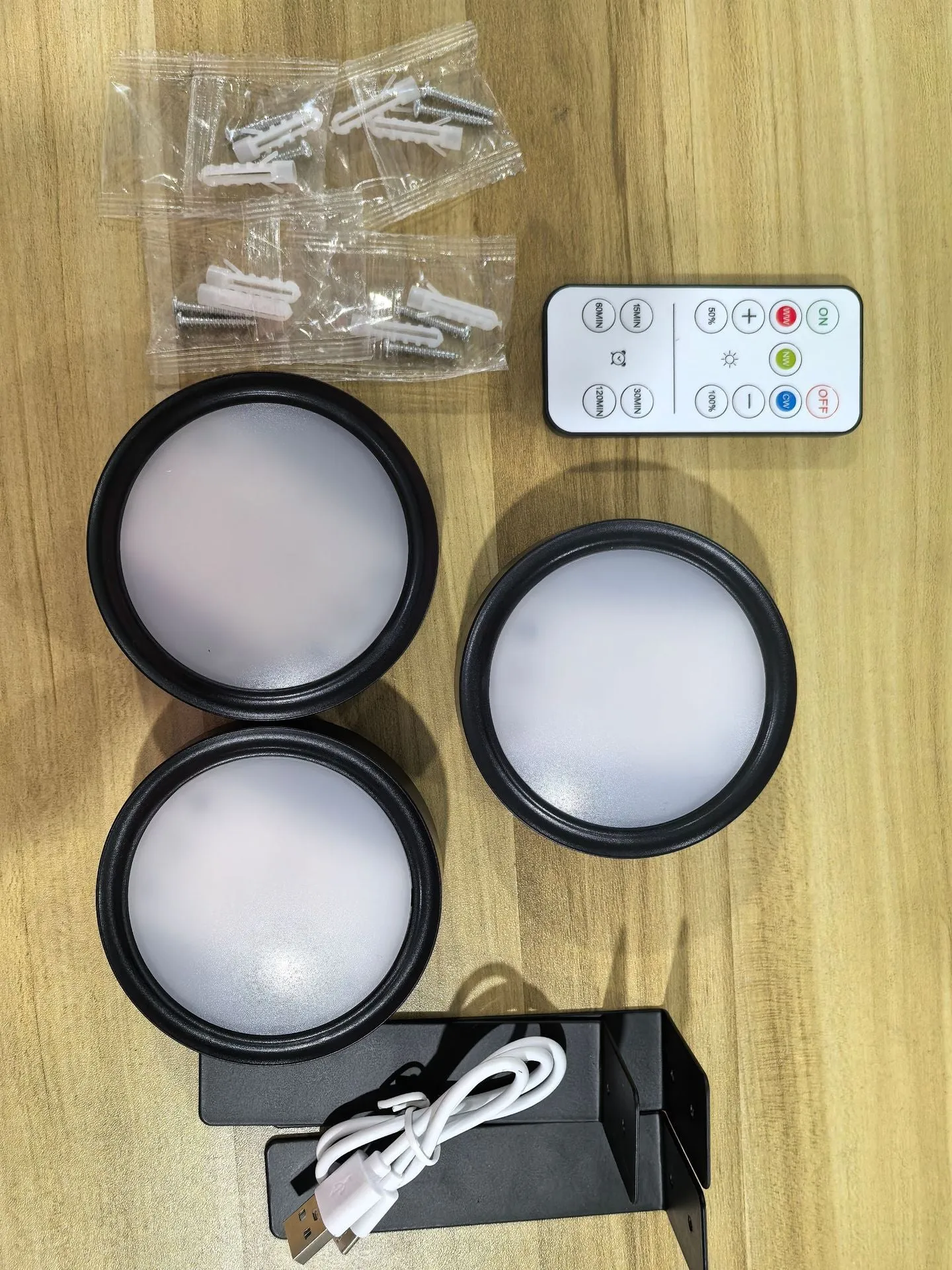 Magnetic LED light bars mounted around a painting, with a remote control on a table nearby.