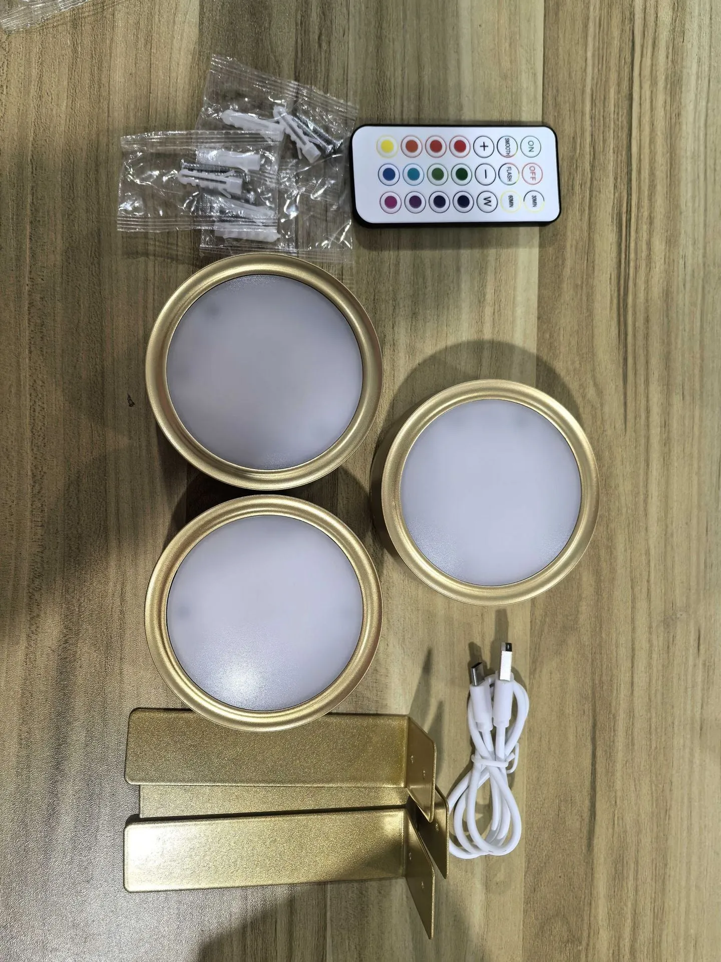 Magnetic LED light bars mounted around a painting, with a remote control on a table nearby.