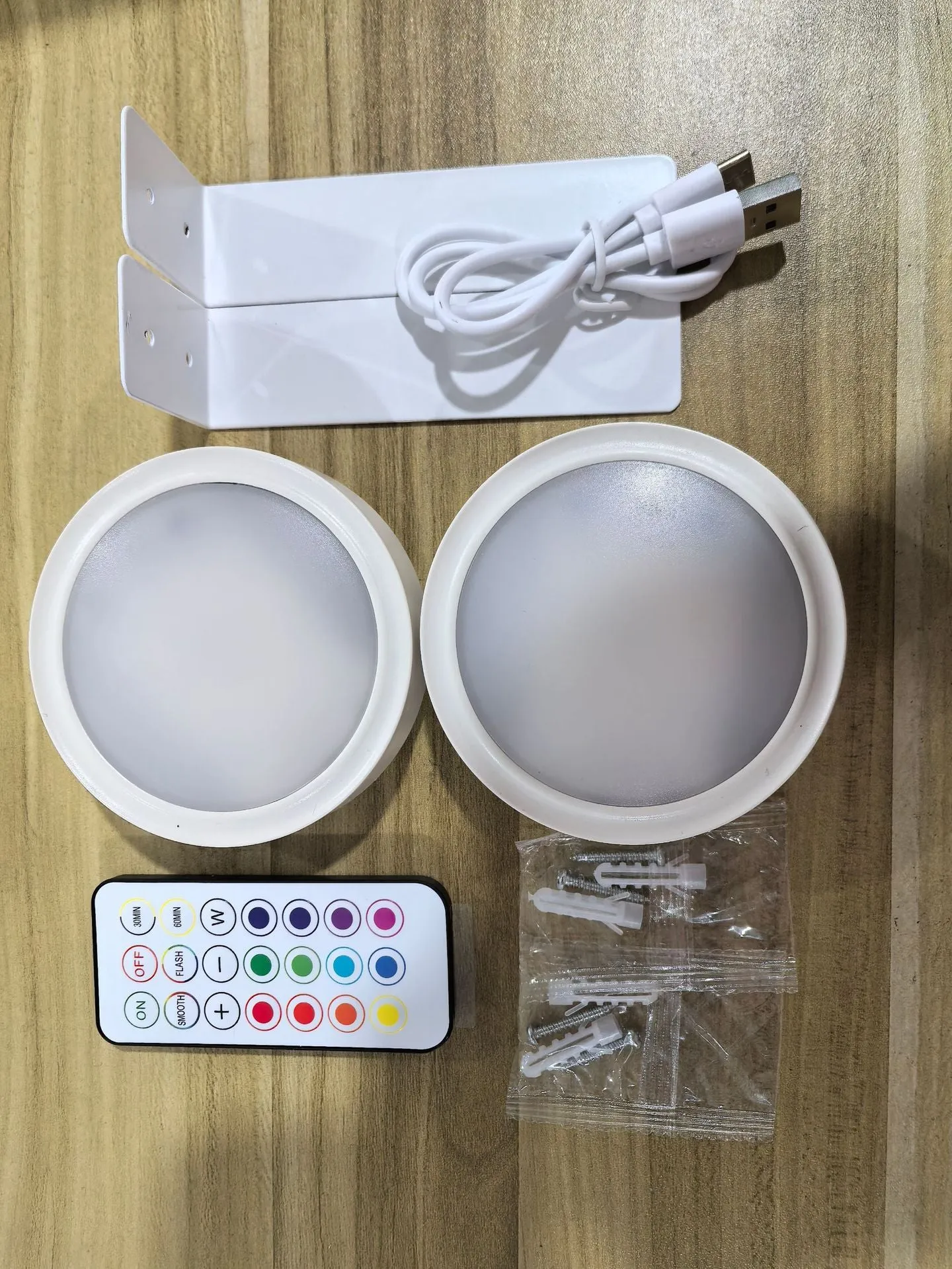 Magnetic LED light bars mounted around a painting, with a remote control on a table nearby.