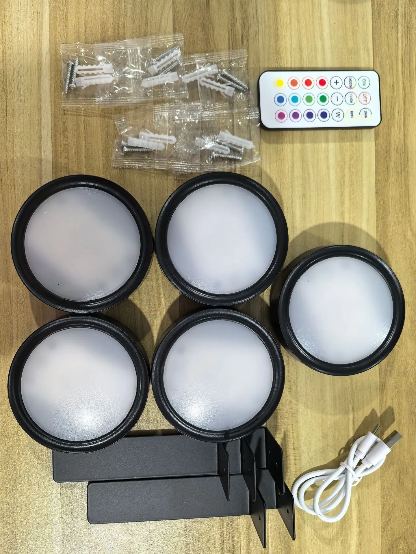 Magnetic LED light bars mounted around a painting, with a remote control on a table nearby.