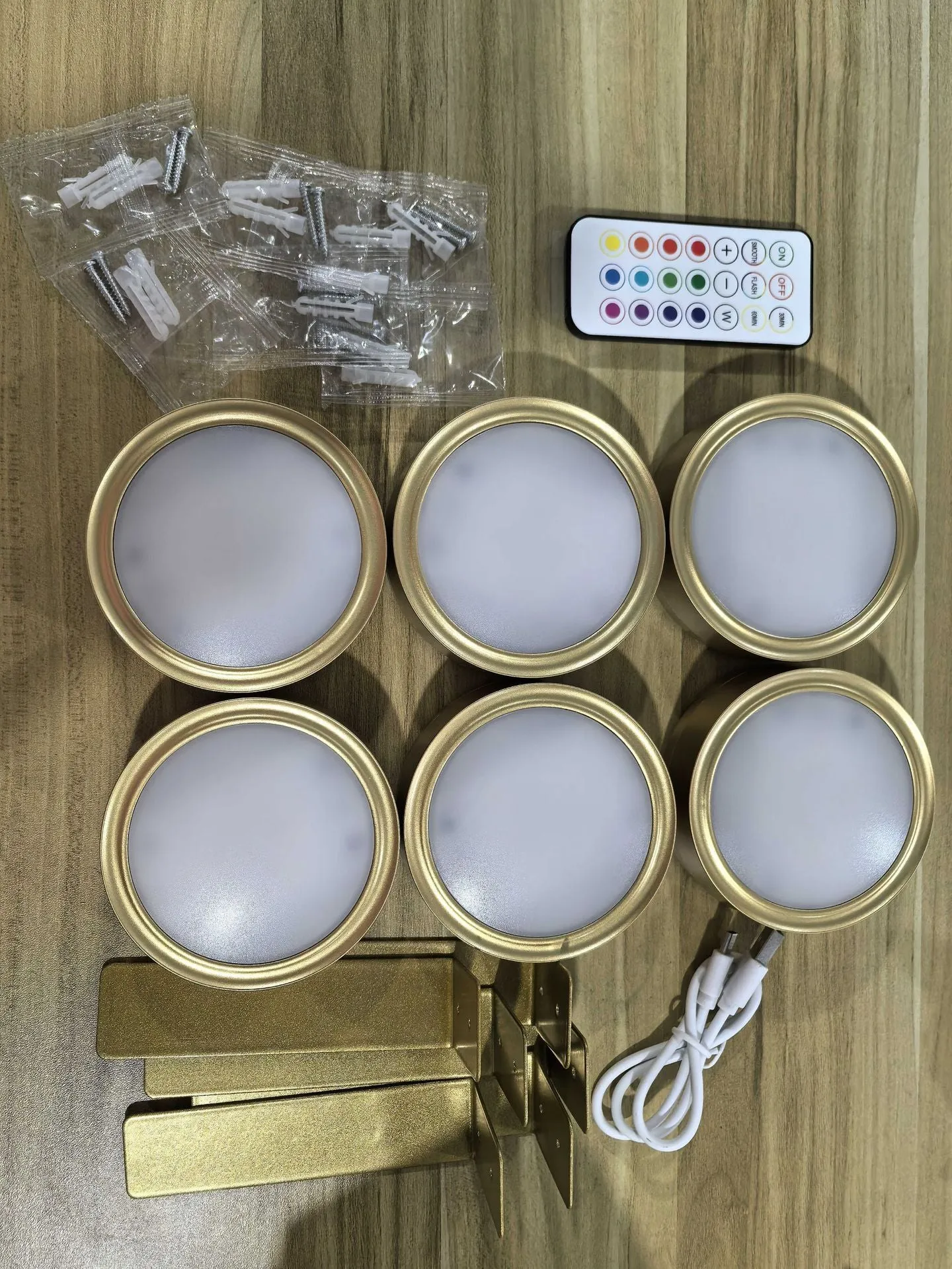 Magnetic LED light bars mounted around a painting, with a remote control on a table nearby.