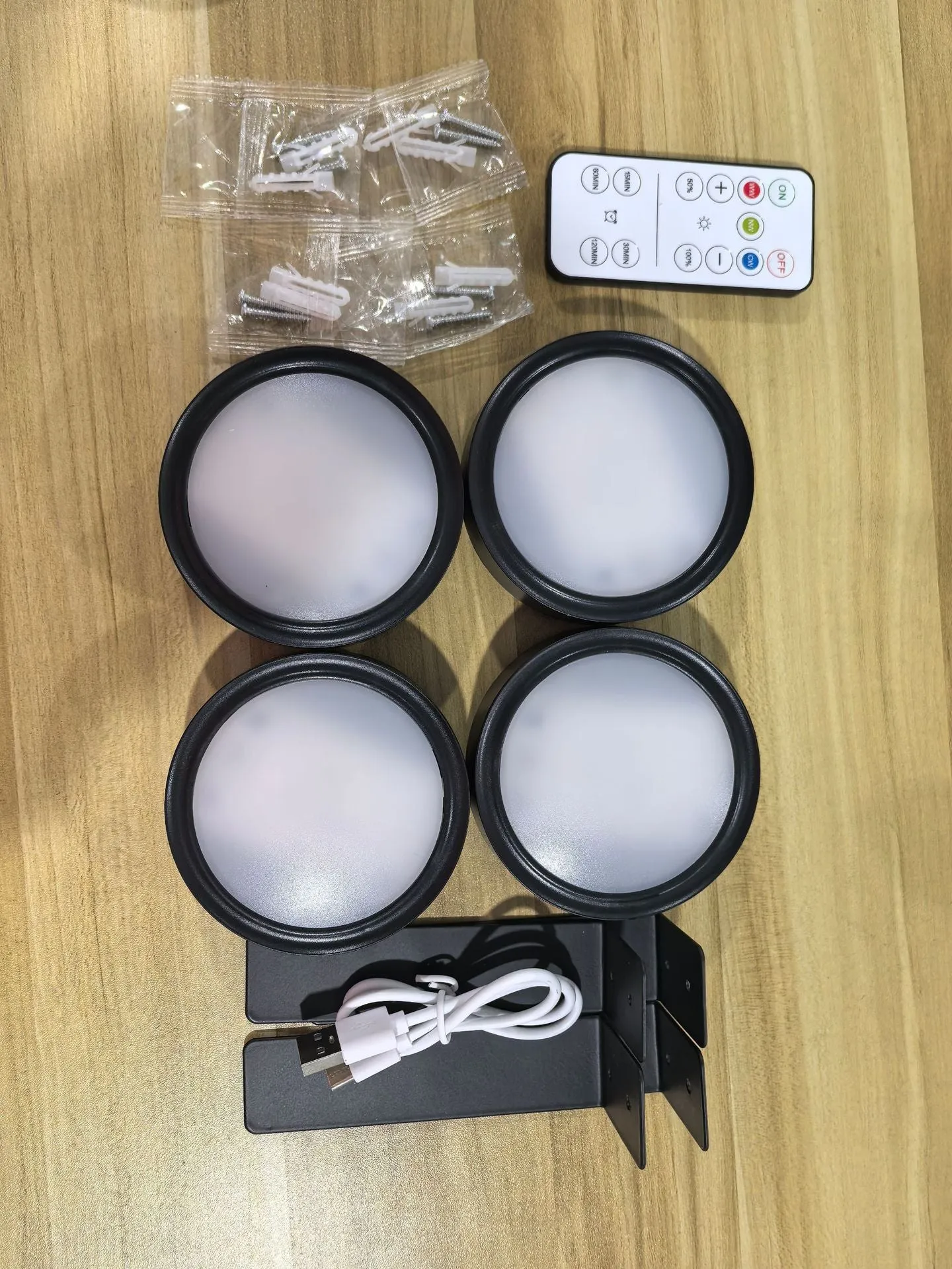 Magnetic LED light bars mounted around a painting, with a remote control on a table nearby.