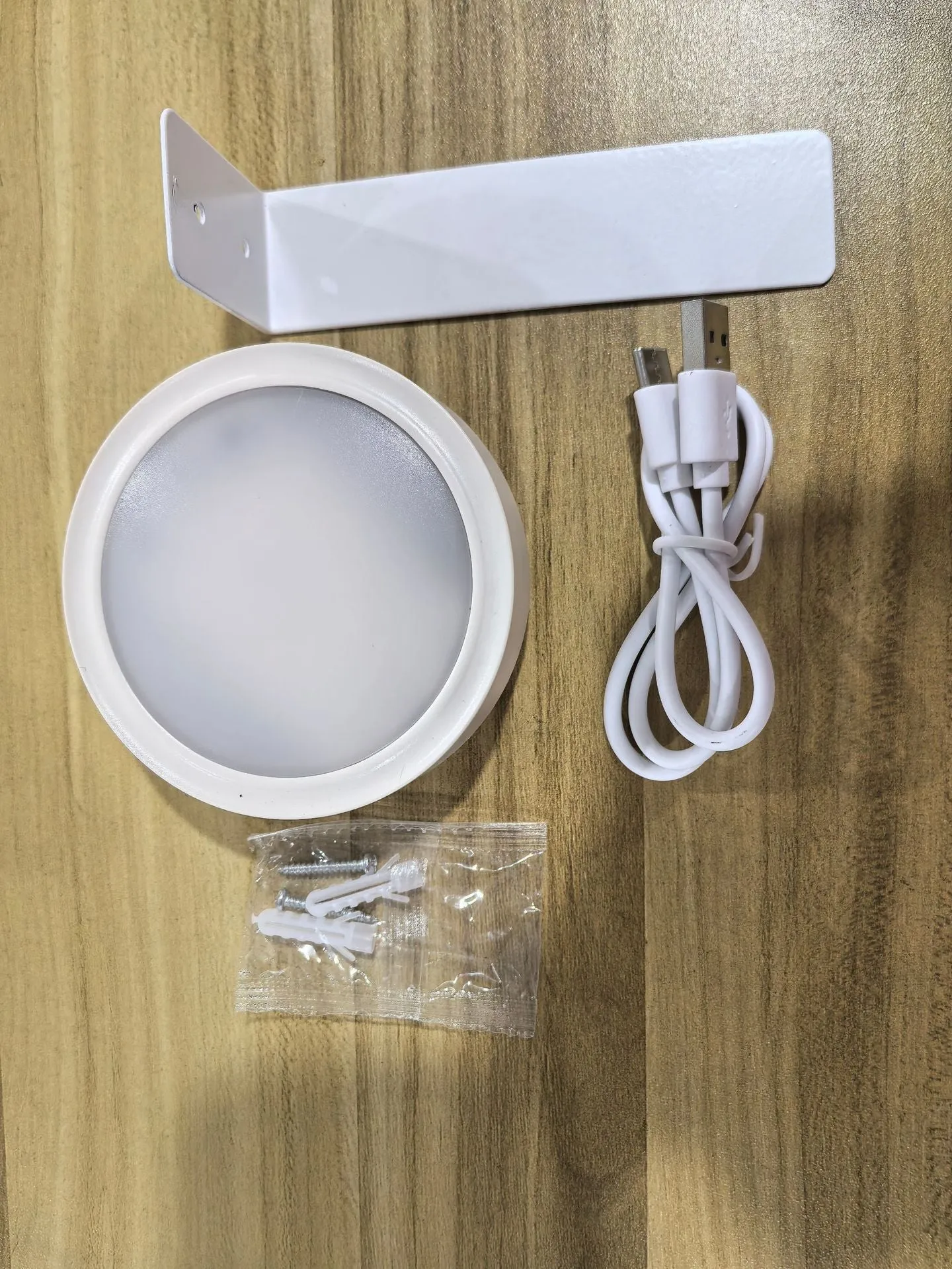 Magnetic LED light bars mounted around a painting, with a remote control on a table nearby.