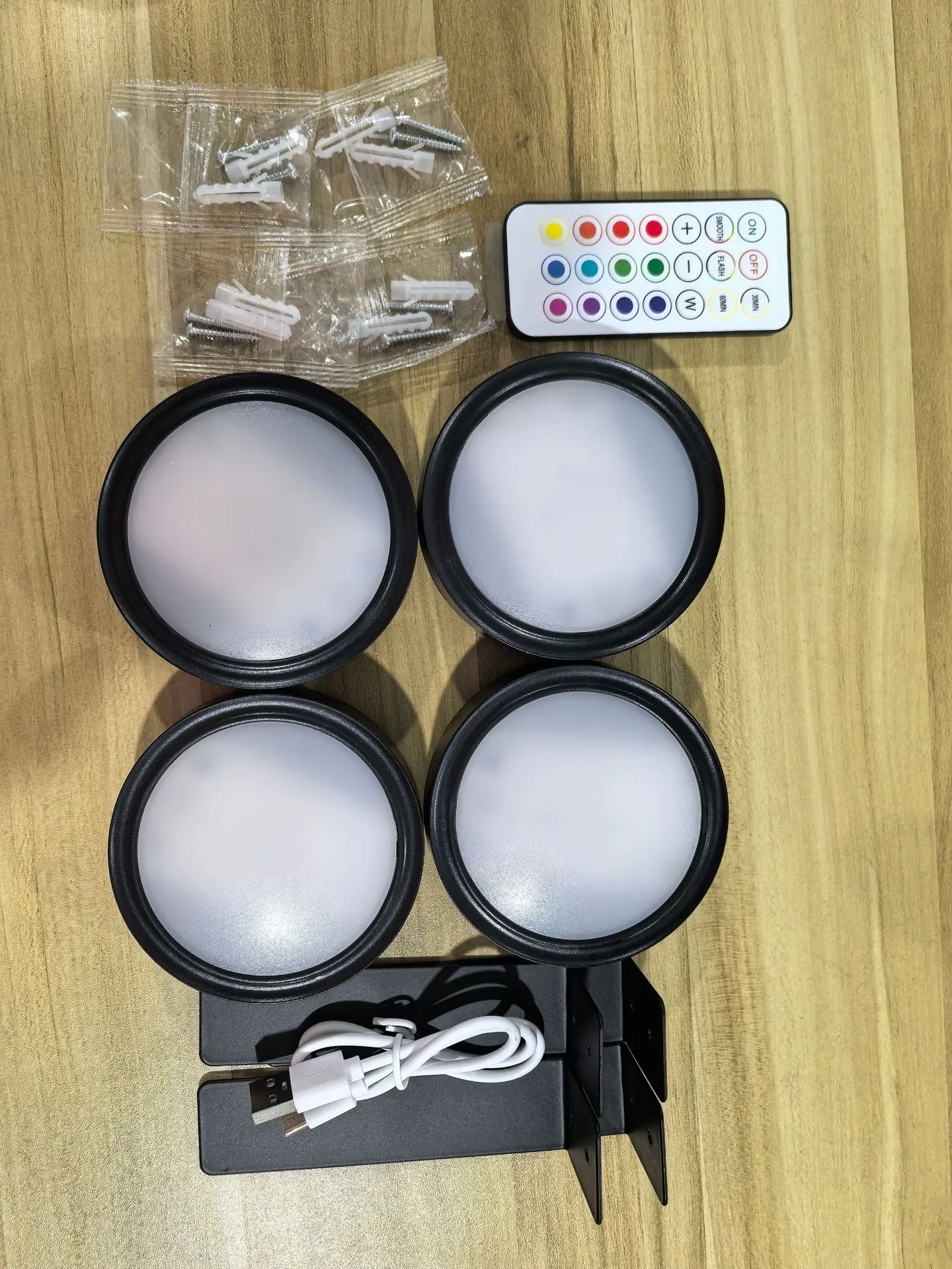 Magnetic LED light bars mounted around a painting, with a remote control on a table nearby.