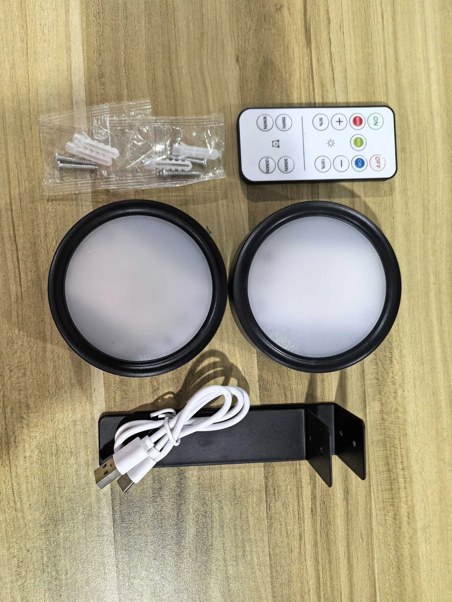 Magnetic LED light bars mounted around a painting, with a remote control on a table nearby.